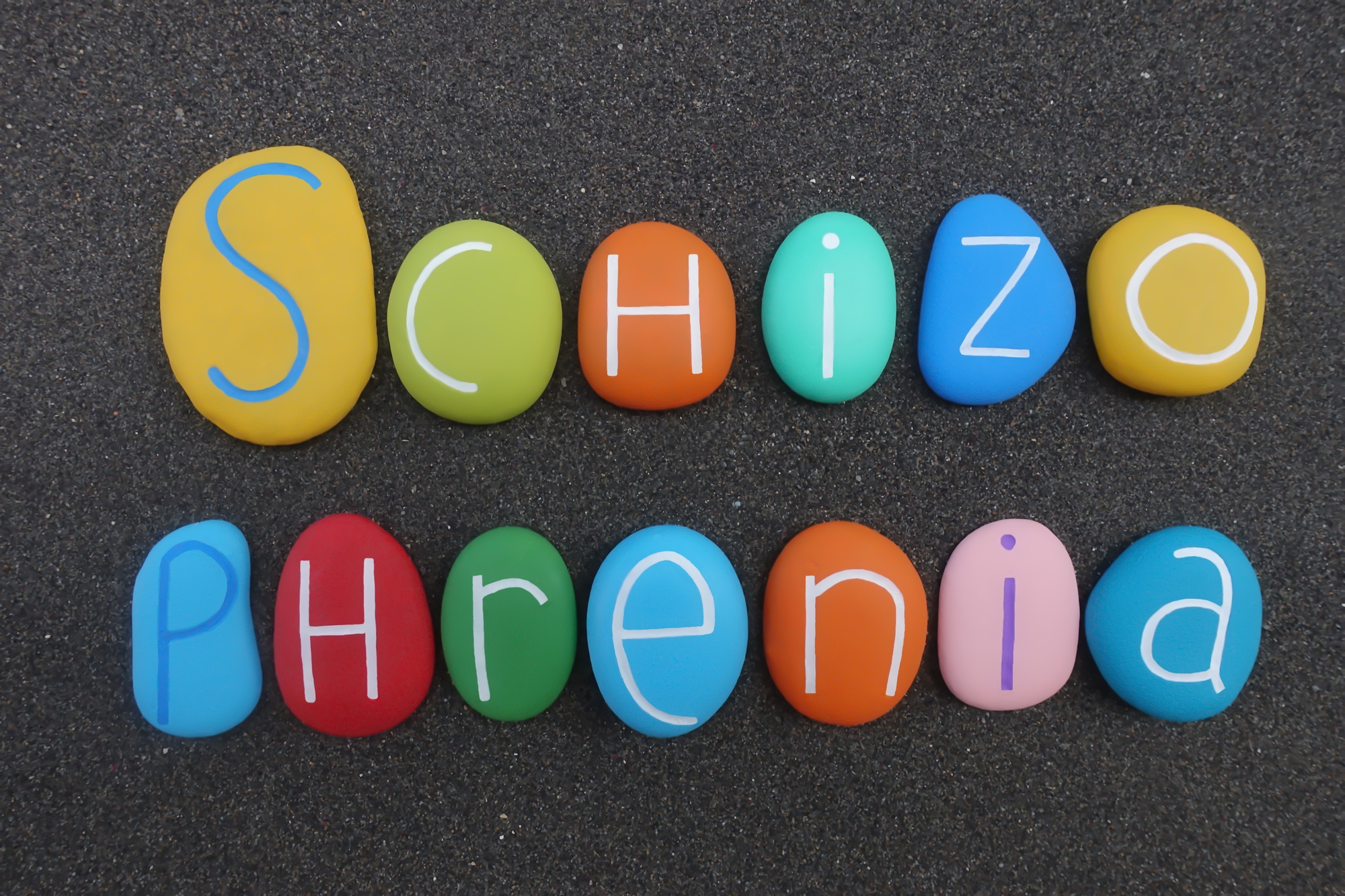 Schizophrenia word composed with multi colored letters over black sand